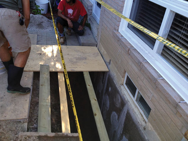 Wokers waterproofing a foundation.